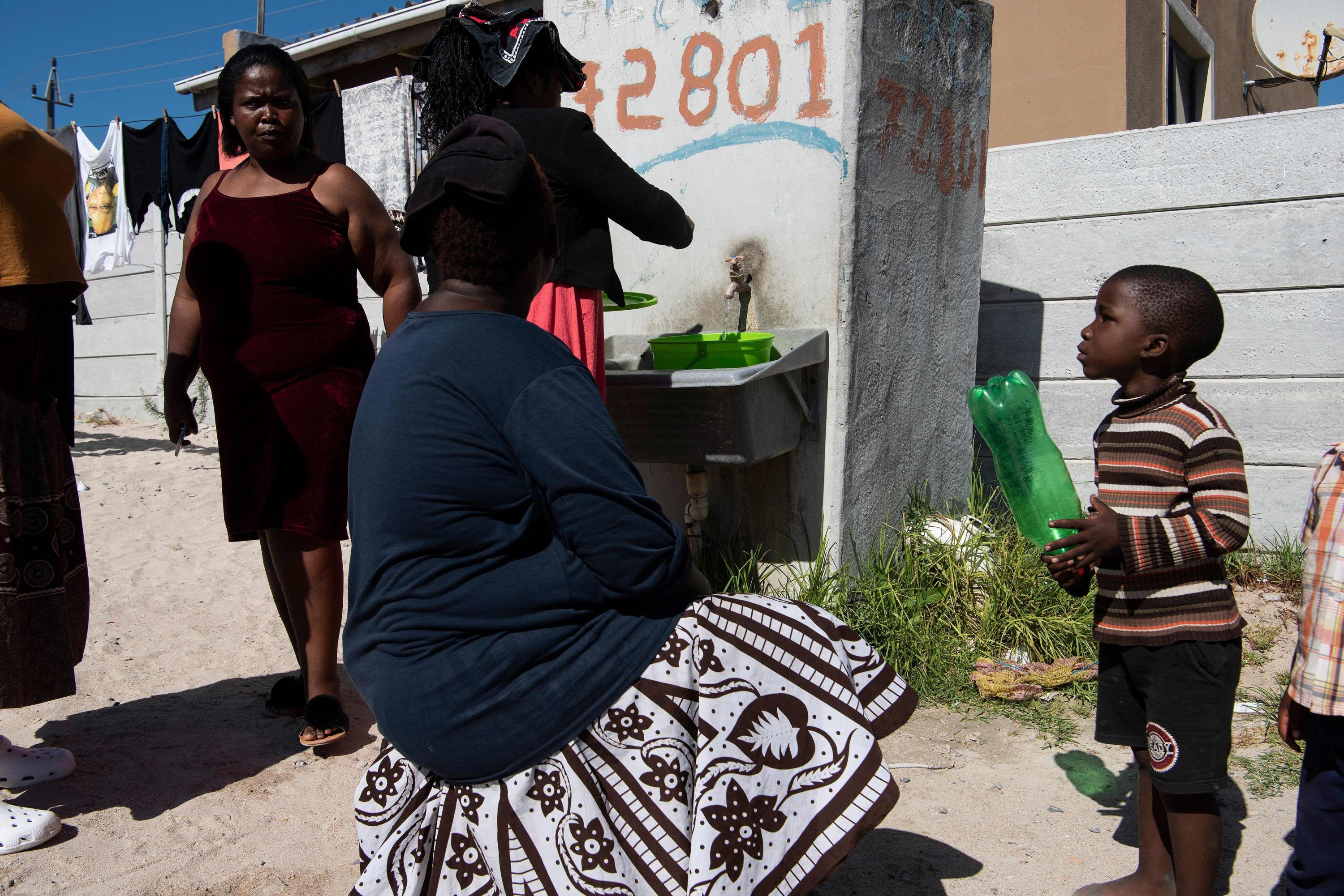 Orang-orang mengisi ember mereka dengan air di salah satu dari sedikit keran yang berfungsi di Zwelitsha, sebuah pemukiman informal di Khayelitsha yang merupakan rumah bagi jutaan orang dalam keadaan miskin, dekat Cape Town, Afrika Selatan, 24 Februari 2022. (AFP Photo)