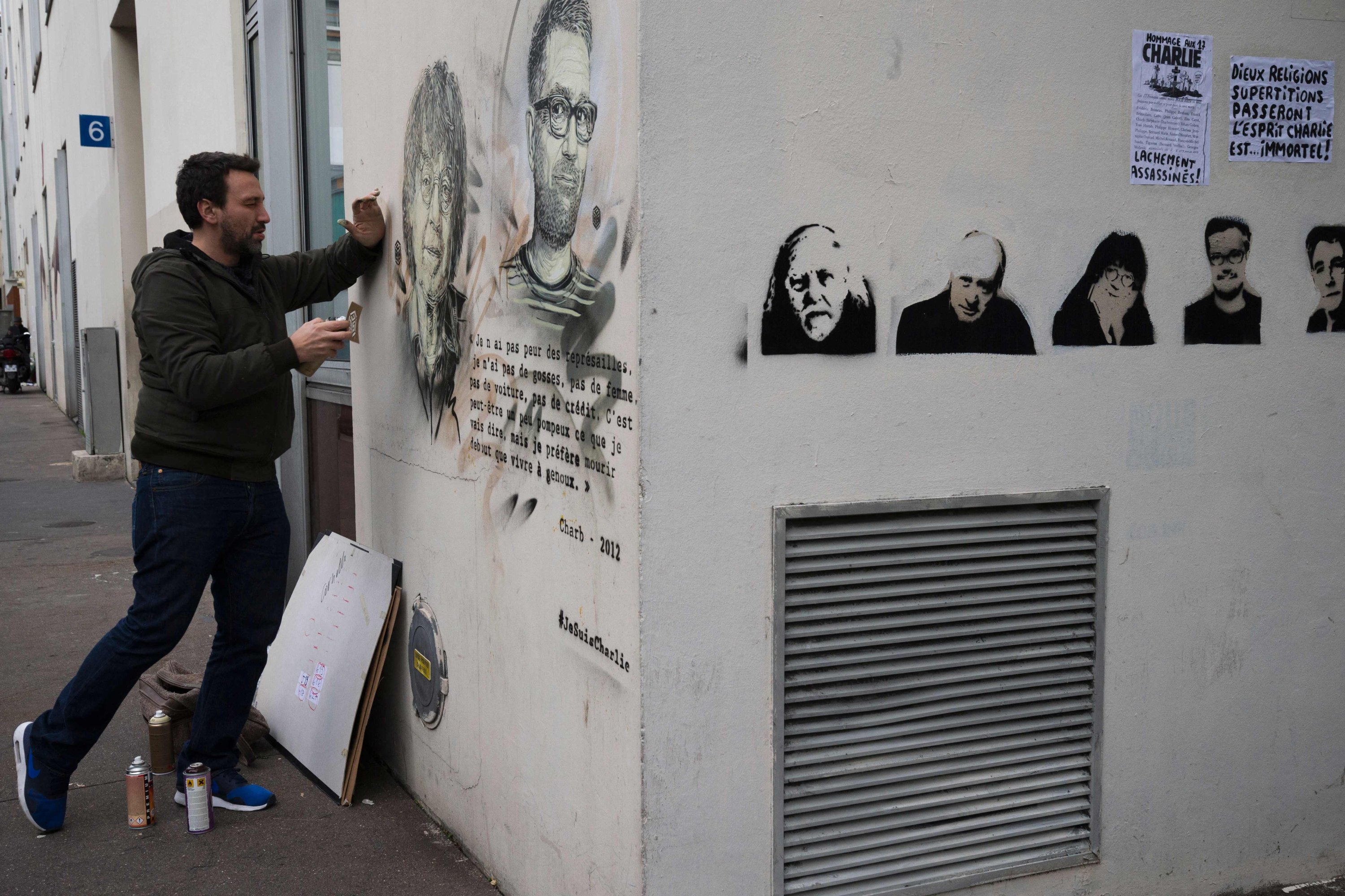 Seniman jalanan Prancis Christian Guemy (C215) memberikan sentuhan akhir pada potret stensil mendiang kartunis Charlie Hebdo Prancis Cabu (kiri) dan Charb (kanan) di dinding depan bekas kantor surat kabar satir di Paris, Prancis, 13 Januari 2016 (Foto File AFP)