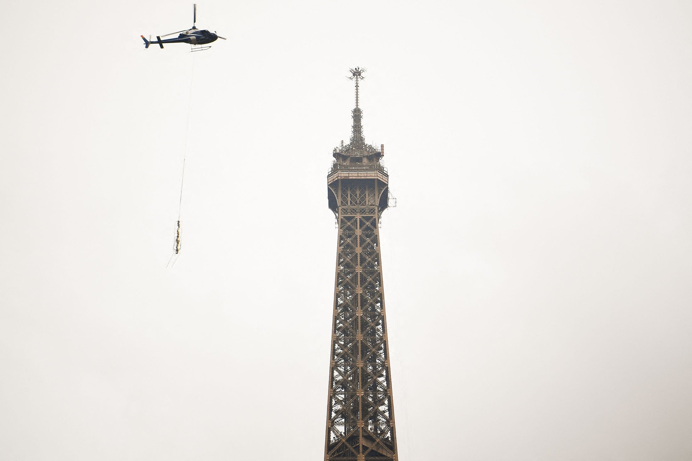 Antena baru dipasang oleh Eurocopter AS355N Ecureuil 2 di puncak Menara Eiffel, di Paris, Prancis, 15 Maret 2022. (AFP Photo)
