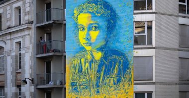 French street artist and painter Christian Guemy (R), known as C215, poses in front of his fresco depicting a young Ukrainian girl with a quote attributed to Ukrainian President Volodymyr Zelenskyy, Paris, France, March 10, 2022. (AFP File Photo)