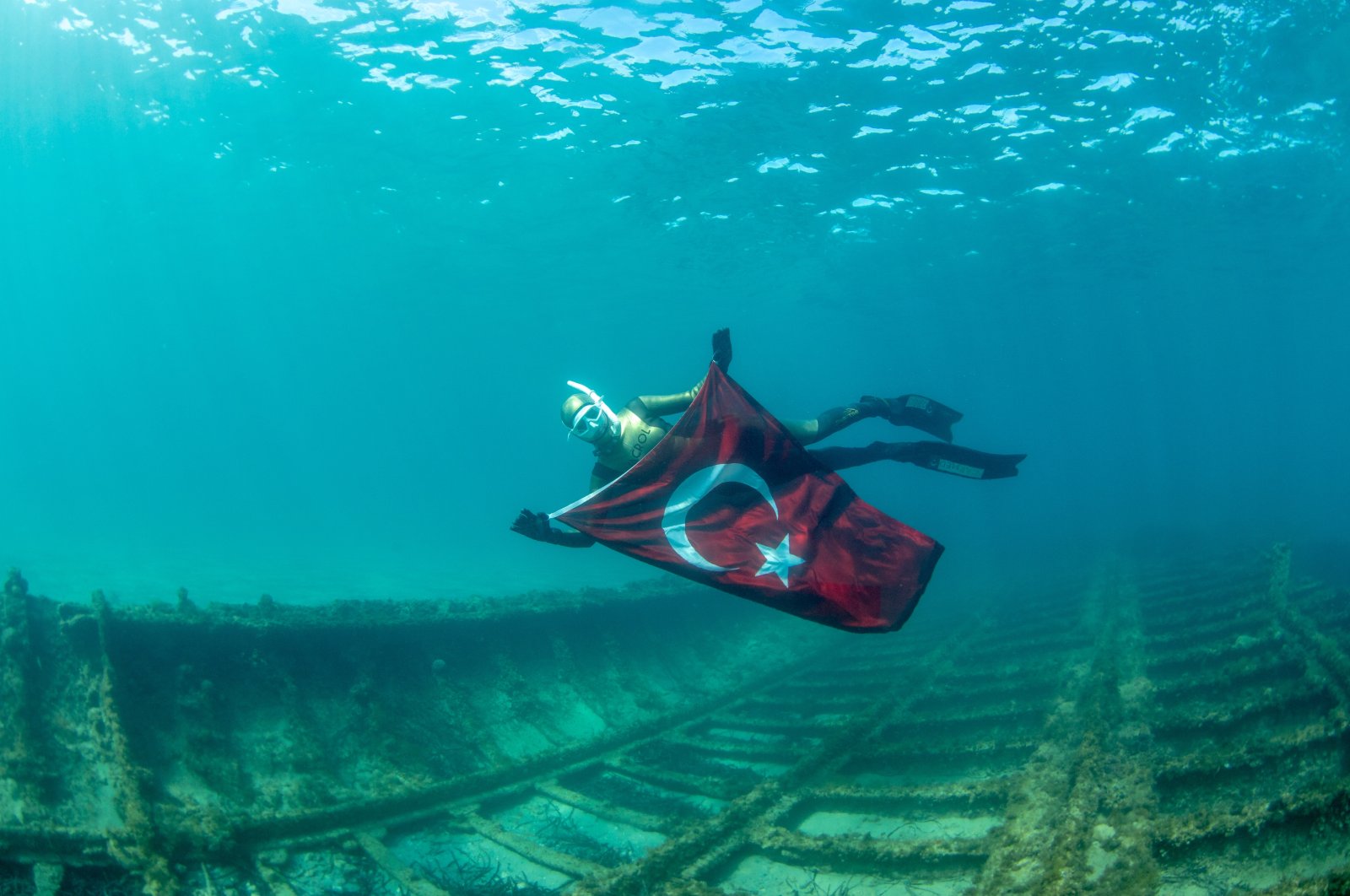 Birgül Erken poses with the Turkish flag above the shipwreck, in Çanakkale, western Turkey, March 15, 2022. (AA PHOTO)
