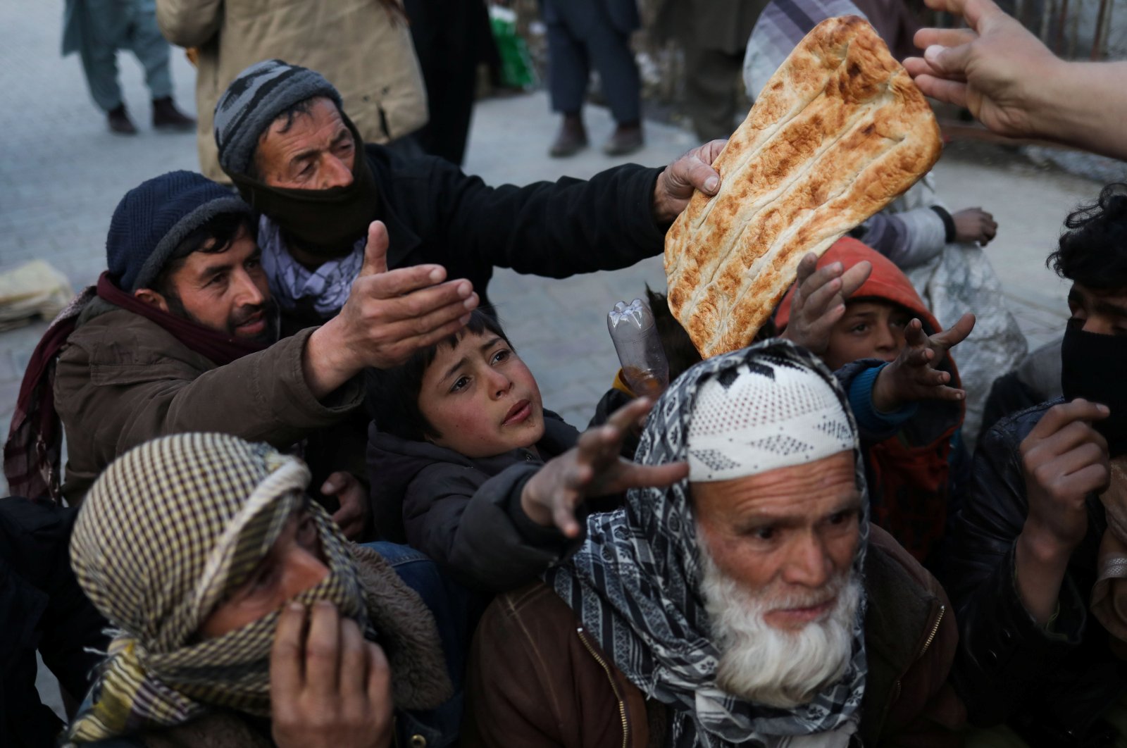People reach out to receive bread, in Kabul, Afghanistan, Jan. 31, 2022. (Reuters Photo)