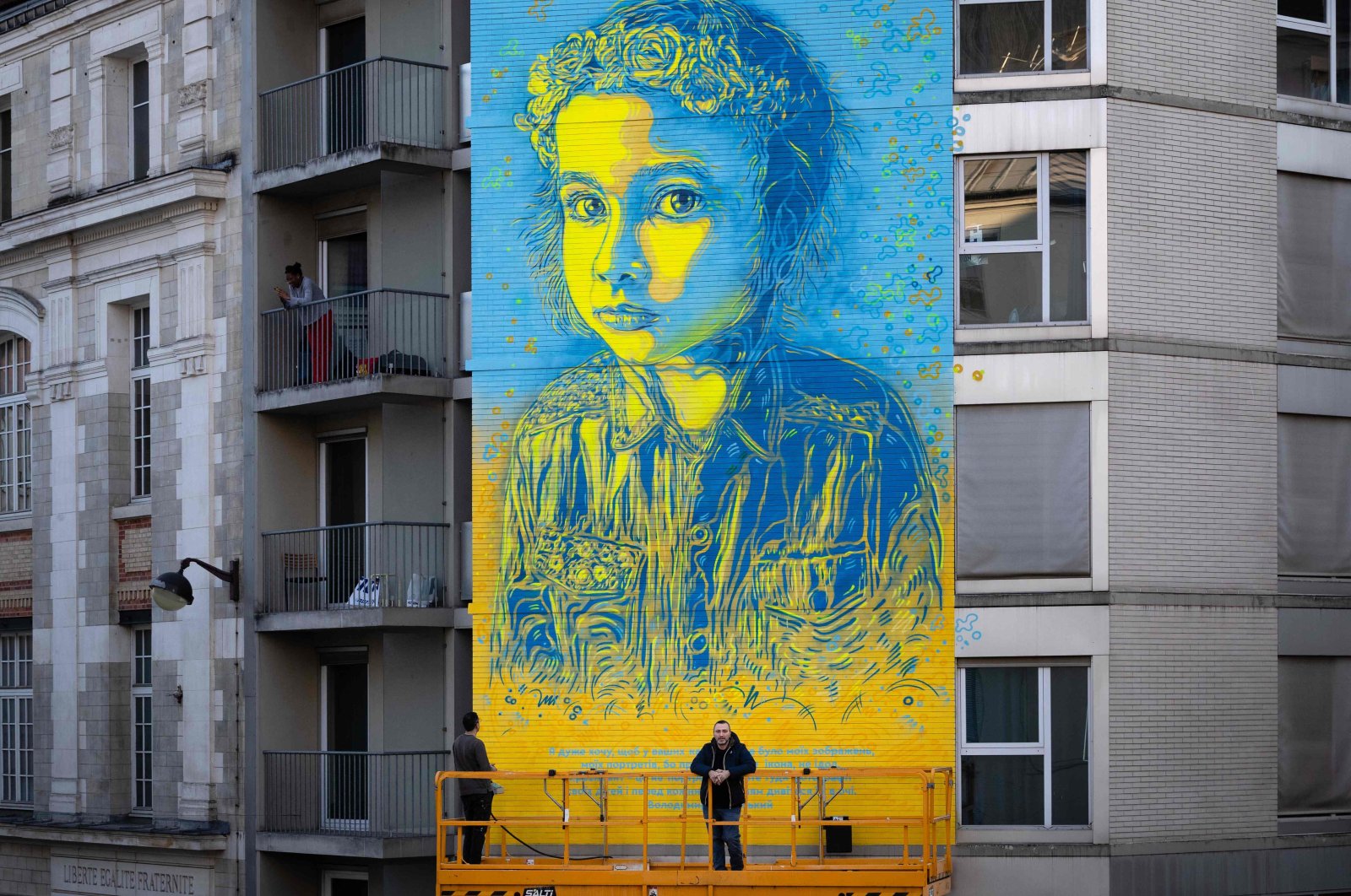 French street artist and painter Christian Guemy (R), known as C215, poses in front of his fresco depicting a young Ukrainian girl with a quote attributed to Ukrainian President Volodymyr Zelenskyy, Paris, France, March 10, 2022. (AFP File Photo)