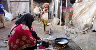 A woman cooks at a makeshift camp for internally displaced people (IDPs) in Aden, Yemen, March 15, 2022. (Reuters Photo)