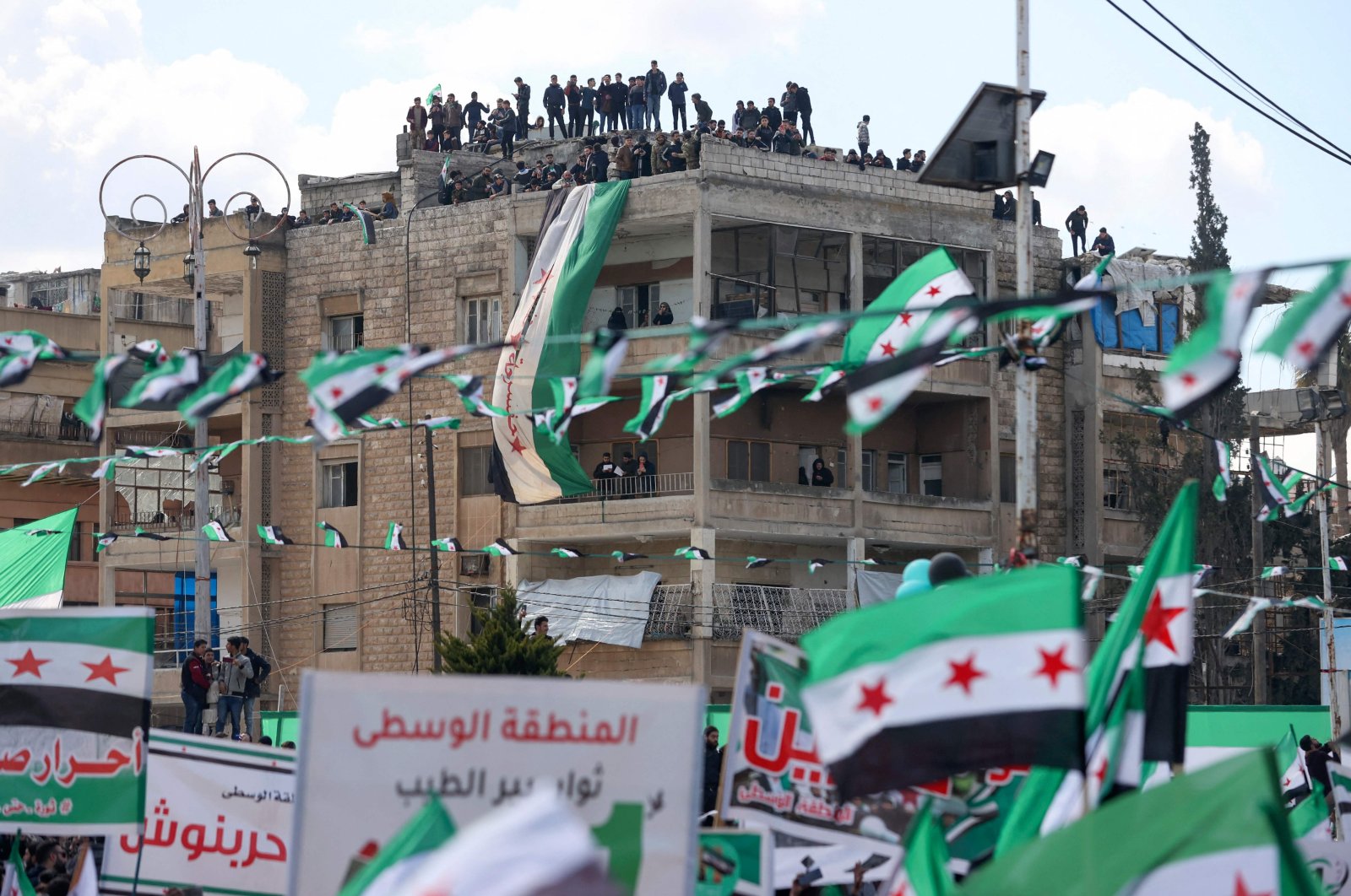 Syrians lift flags during a rally marking 11 years since the start of an anti-regime uprising in Idlib, northwestern Syria, March 15, 2022. (AFP)