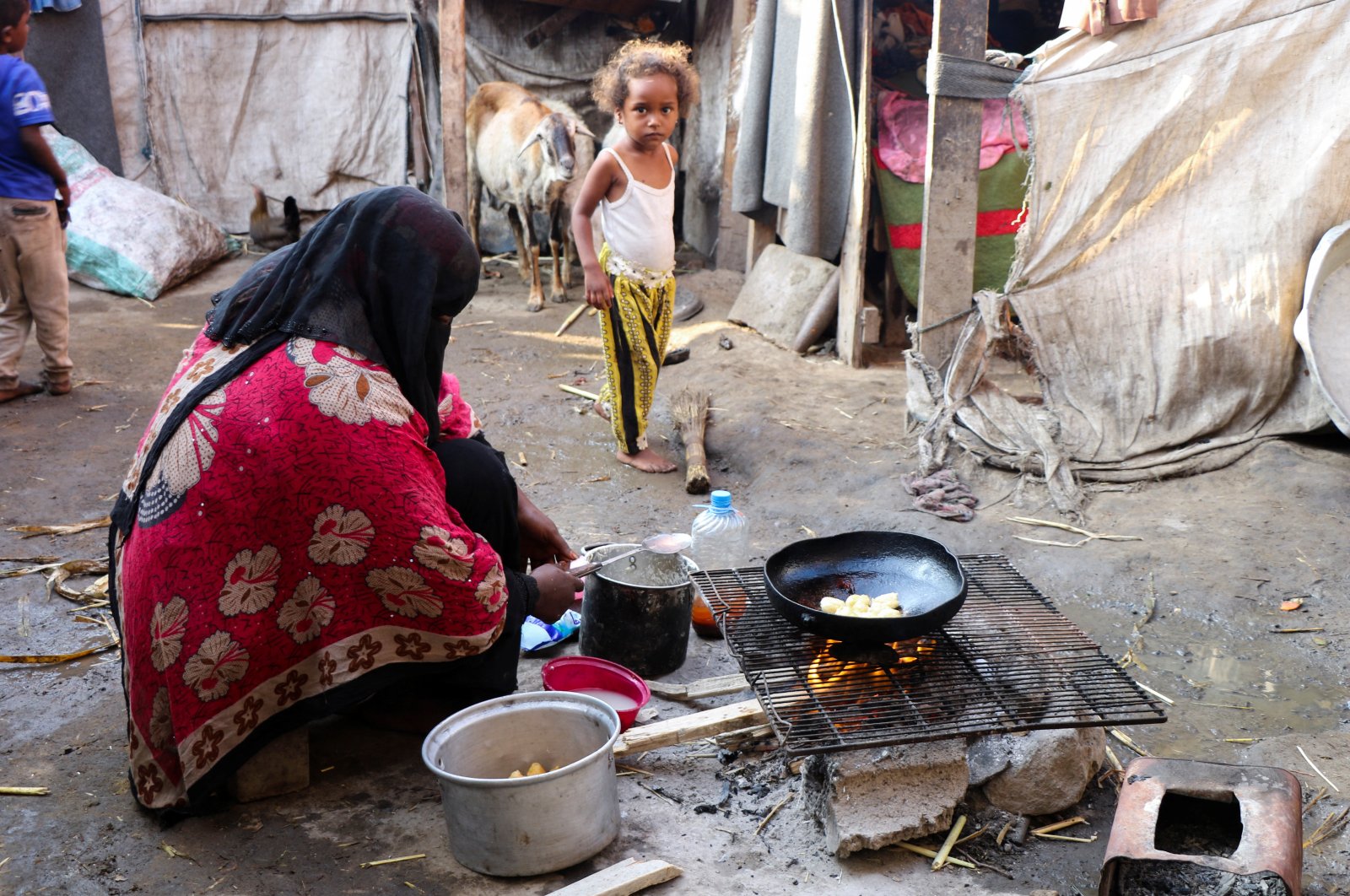 A woman cooks at a makeshift camp for internally displaced people (IDPs) in Aden, Yemen, March 15, 2022. (Reuters Photo)