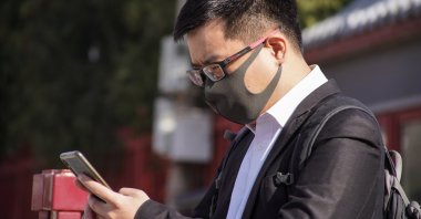 A man wearing a face mask uses his mobile phone in Beijing, China, March 14, 2022. (EPA Photo)