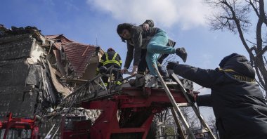 Firefighters help a woman to evacuate from a damaged by shelling apartment building in Mariupol, Ukraine, March 10, 2022. (AP Photo)