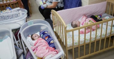 Nurse Antonina Yefymovych feeds a surrogate-born baby inside a special shelter owned by BioTexCom clinic in a residential basement, Kyiv, Ukraine, March 15, 2022. (Reuters Photo)