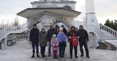Turkish imam Mehmet Yüce holds a Turkish flag and stands with Turkish nationals to pose for a picture in front of the mosque in Mariupol, Ukraine, March 12, 2022. (AP Photo)