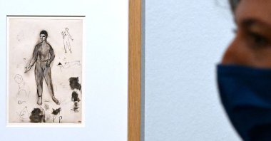 A visitor views "Harlequin, study of the same Harlequin, five dogs, four caricatures of Apollinaire as Father Ubu, a caricature of Henri Delormel," a 1905 drawing by Spanish painter Pablo Picasso, at the exhibition "Scribbling and Doodling: From Leonardo da Vinci to Cy Twombly" ("Gribouillage - Scarabocchio. Da Leonardo da Vinci a Cy Twombly") at the Villa Medici, Rome, Italy, March 17, 2022. (Photo by Alberto PIZZOLI / AFP)