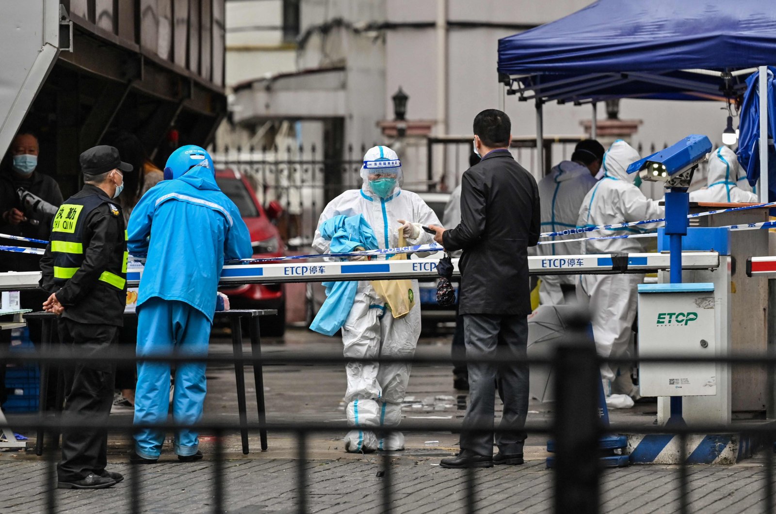 A delivery man (L in blue) is seen arriving to deliver an order outside of a locked-down neighborhood after the detection of new cases of COVID-19 in Huangpu district, in Shanghai, China, March 17, 2022. (AFP Photo)