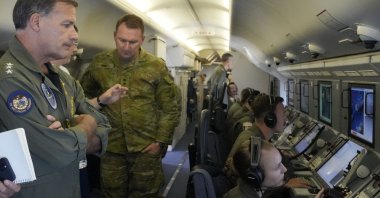 Admiral John C. Aquilino (L), Commander of the U.S. Indo-Pacific Command, looks at videos of Chinese structures and buildings on board a U.S. P-8A Poseidon reconaisance plane flying at the Spratlys group of islands in the South China Sea, March 20, 2022. (AP Photo)