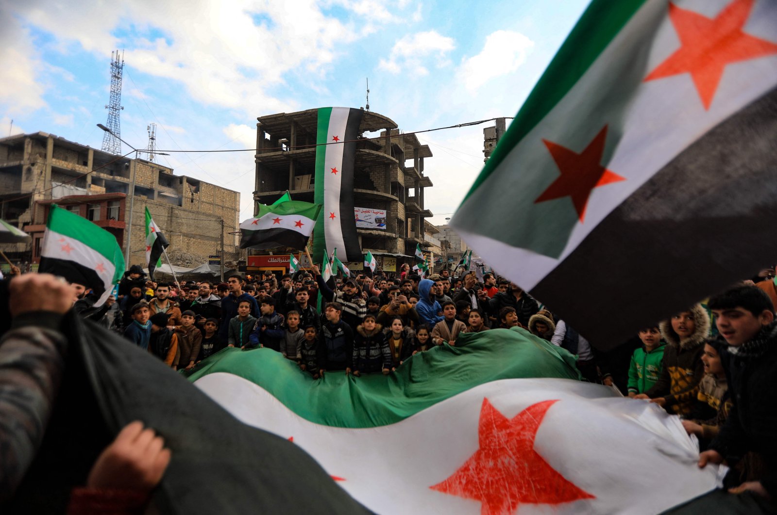 People wave opposition flags at a rally marking 11 years since the start of an anti-regime uprising, in the city of al-Bab in Syria&#039;s Aleppo governorate on March 18, 2022 (AFP Photo)