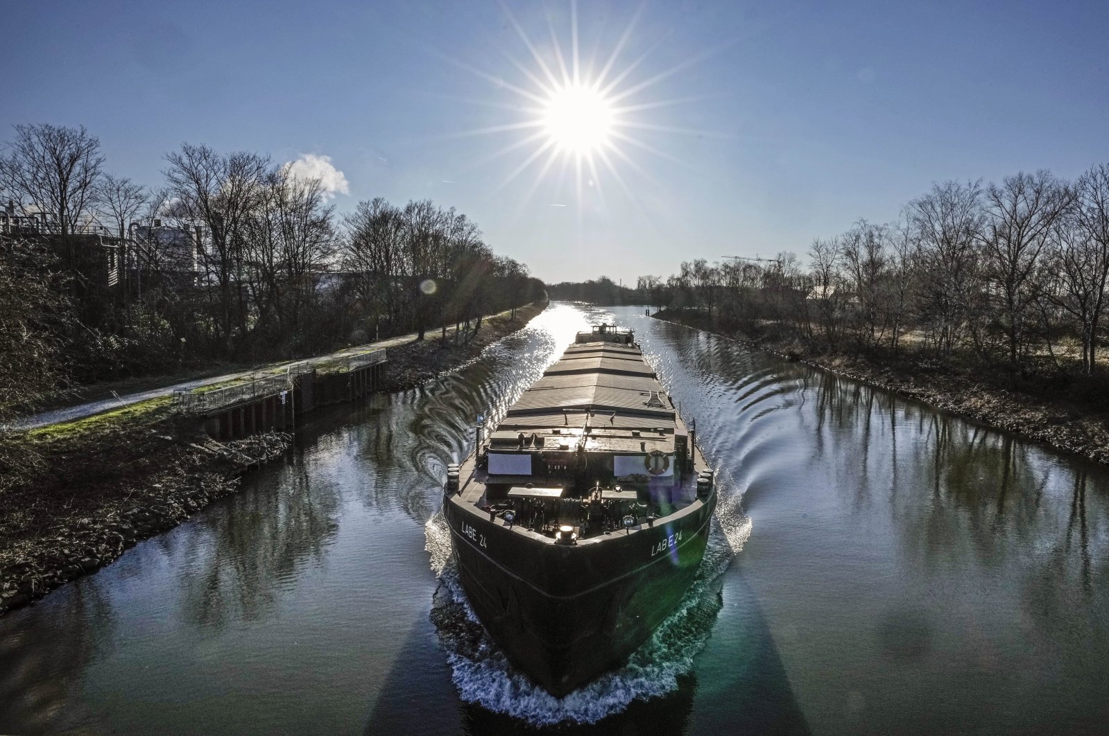 A freight ship operates on a canal on a sunny Tuesday, Gelsenkirchen, Germany, March 8, 2022. (AP Photo)
