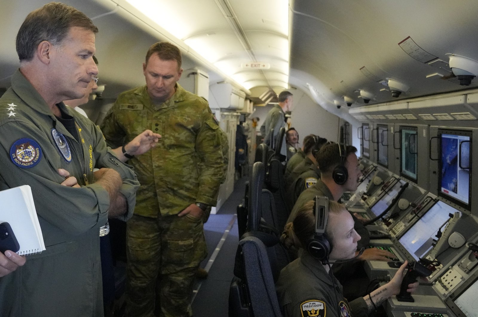 Admiral John C. Aquilino (L), Commander of the U.S. Indo-Pacific Command, looks at videos of Chinese structures and buildings on board a U.S. P-8A Poseidon reconaisance plane flying at the Spratlys group of islands in the South China Sea, March 20, 2022. (AP Photo)