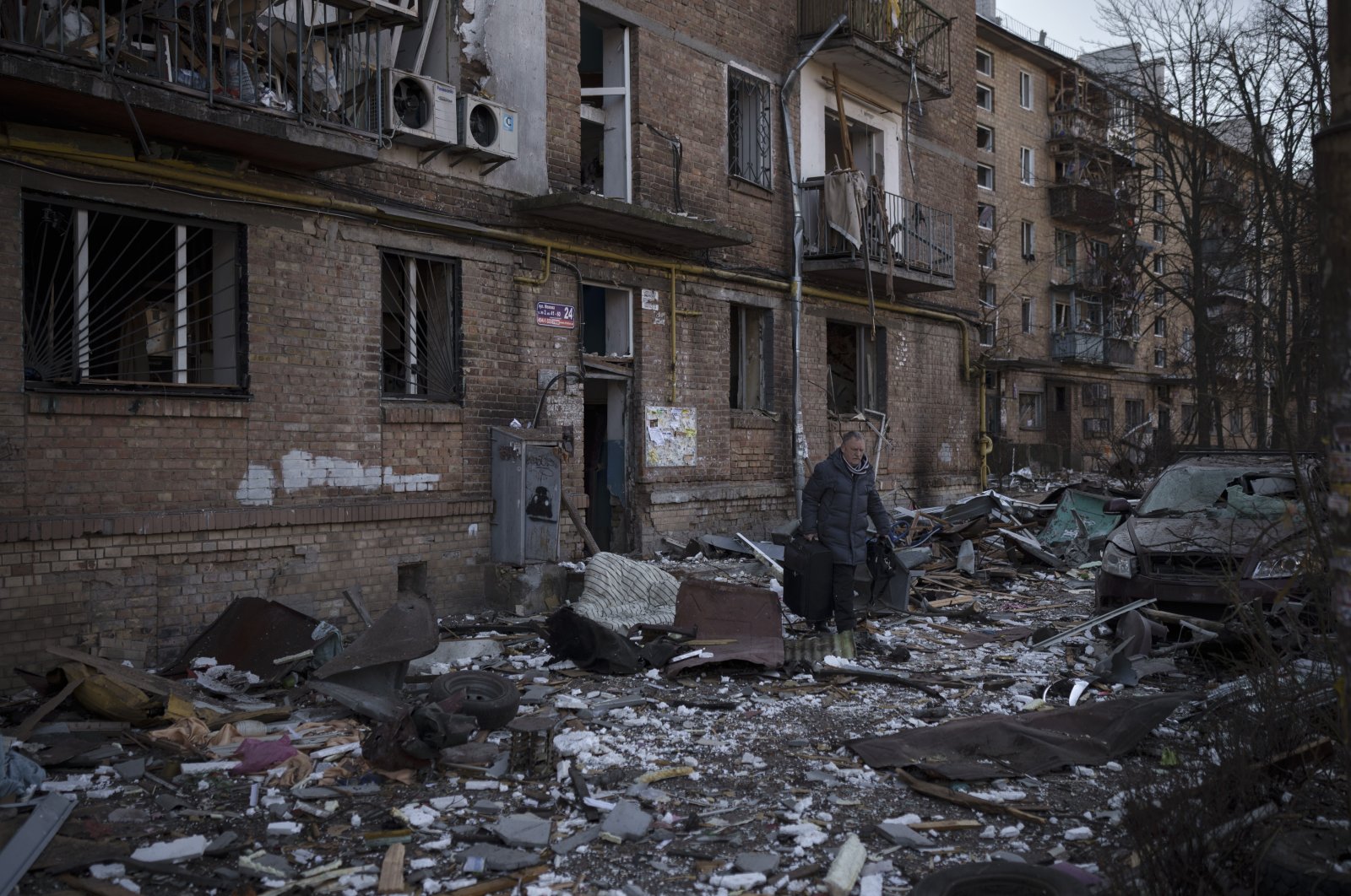 A resident carries a suitcase with his belongings after his building was heavily damaged by Russian bombing in Kyiv, Ukraine, Friday, March 18, 2022. (AP File Photo)