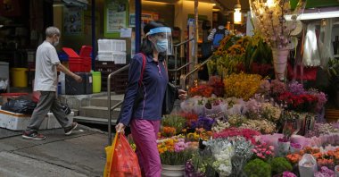 A woman wearing a face mask walks past a flower store in Hong Kong, March 22, 2022. (AP Photo)