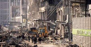 Ukrainian firefighters and soldiers work next to a digger amid the rubble of the Retroville shopping mall, a day after it was shelled by Russian forces in a residential district in the northwest of the Ukranian capital Kyiv, March 21, 2022. (AFP Photo)