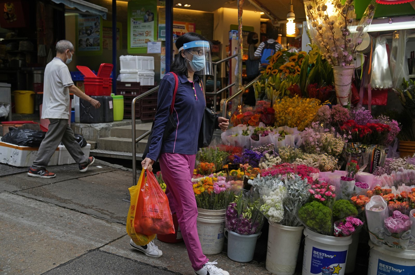 A woman wearing a face mask walks past a flower store in Hong Kong, March 22, 2022. (AP Photo)