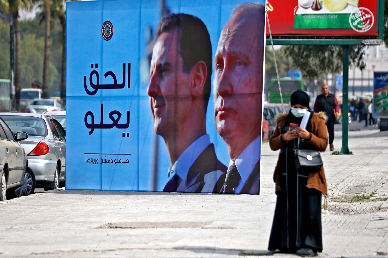 A banner depicting Syrian regime leader Bashar Assad (L) and Russian President Vladimir Putin reading &quot;Justice Prevails&quot; is displayed along a highway in Damascus, Syria, March 8, 2022. (AFP Photo)