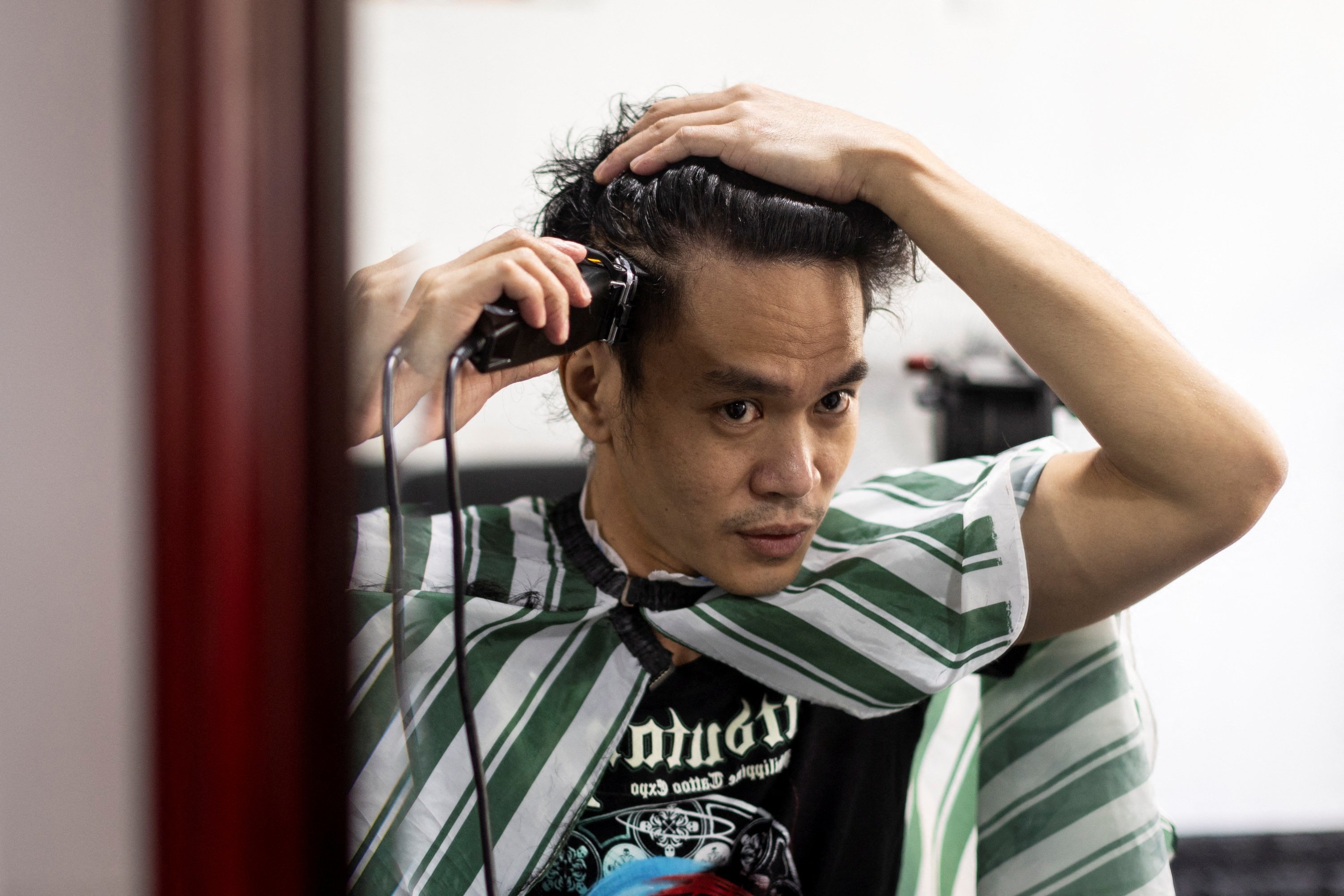 Artis dan pelaut Filipina Jesstoni Garcia mencukur rambutnya untuk membuat potret, di San Juan City, Filipina, 10 Maret 2022. (REUTERS)