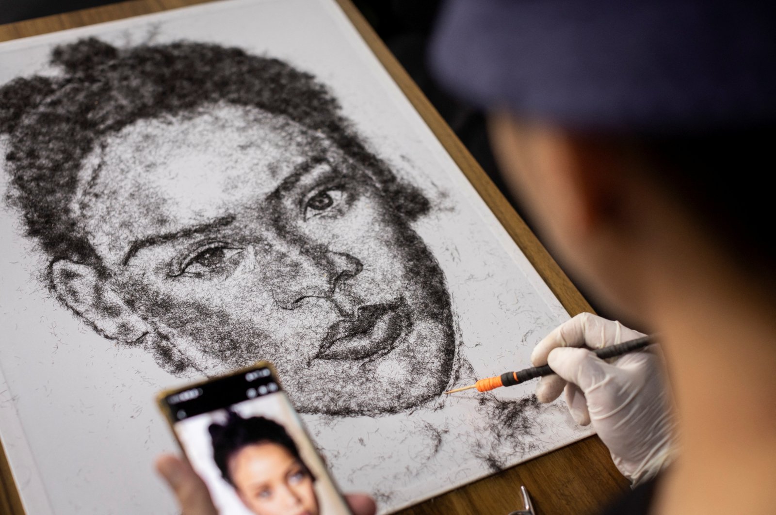 Artist and Filipino seafarer Jesstoni Garcia works on a portrait of Rihanna, made out of human hair, in San Juan City, Philippines, March 10, 2022. (REUTERS)