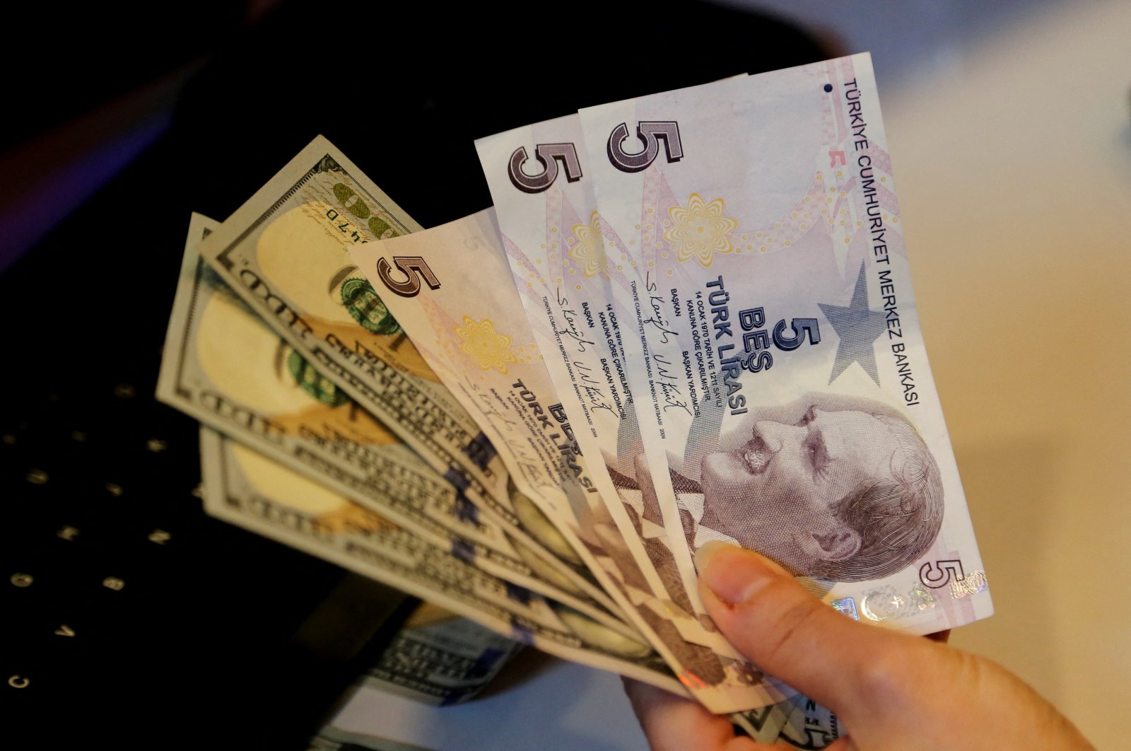 A money changer holds Turkish lira and U.S. dollar banknotes at a currency exchange office in Ankara, Turkey, Dec. 16, 2021. (Reuters Photo)