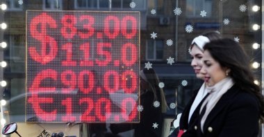People walk past a currency exchange office screen displaying the exchange rates of U.S. dollar and euro to Russian rubles in Moscow&#039;s downtown, Russia, Feb. 28, 2022. (AP Photo)