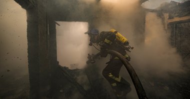 A Ukrainian firefighter sprays water inside a house destroyed by shelling in Kyiv, Ukraine, March 23, 2022. (AP Photo)