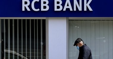 A man uses his cell phone as he walks outside of a branch of RCB, Russian Commercial Bank, in the divided capital of Lefkoşa (Nicosia), the island of Cyprus, March 24, 2022. (AP Photo)