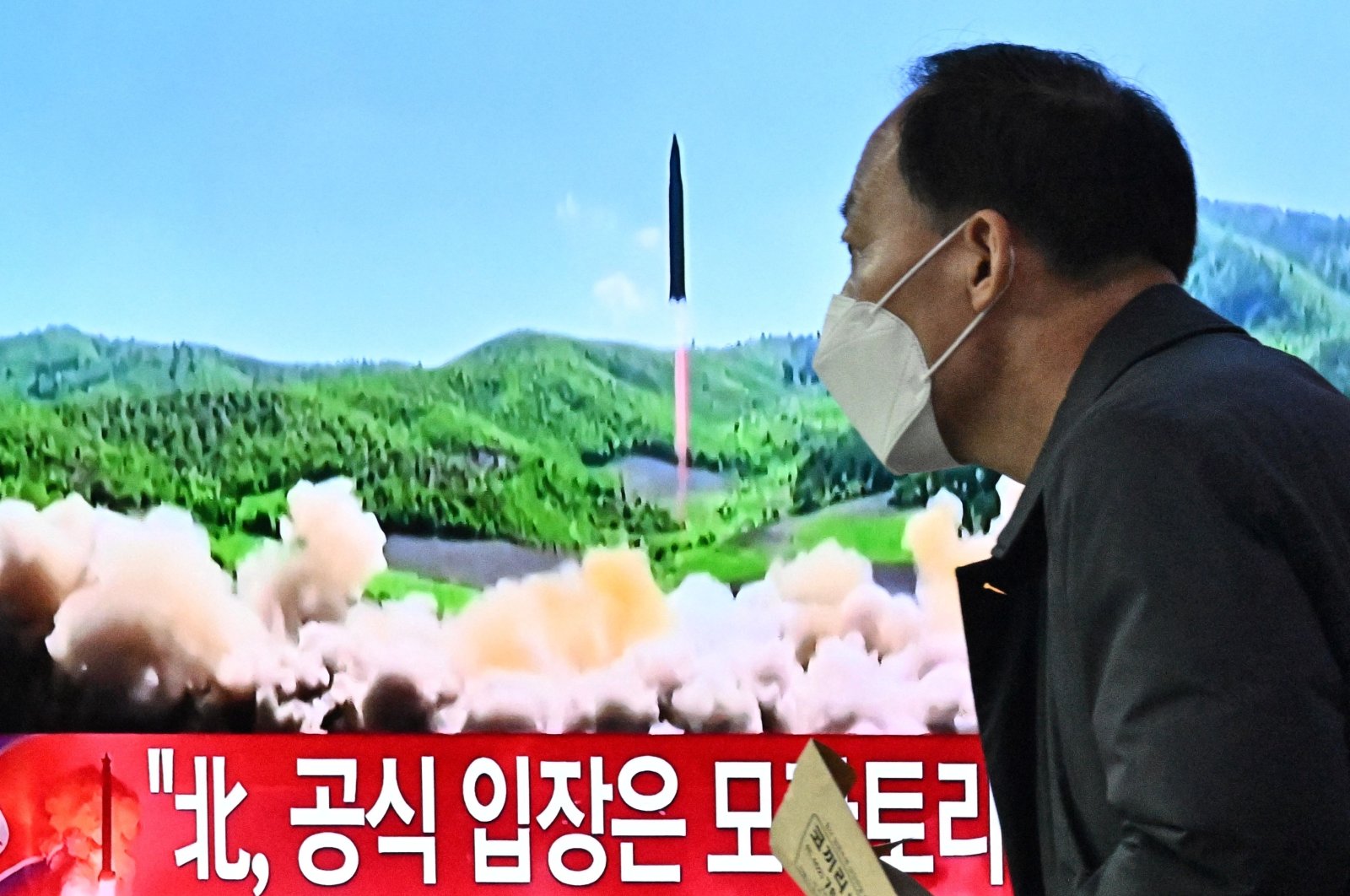 A man walks past a television report showing a news broadcast with file footage of a North Korean missile test, at a railway station in Seoul, South Korea, March 24, 2022. (AFP Photo)