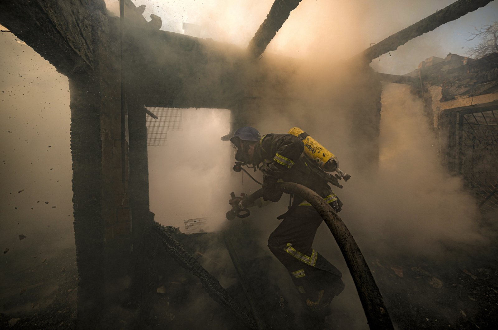 A Ukrainian firefighter sprays water inside a house destroyed by shelling in Kyiv, Ukraine, March 23, 2022. (AP Photo)