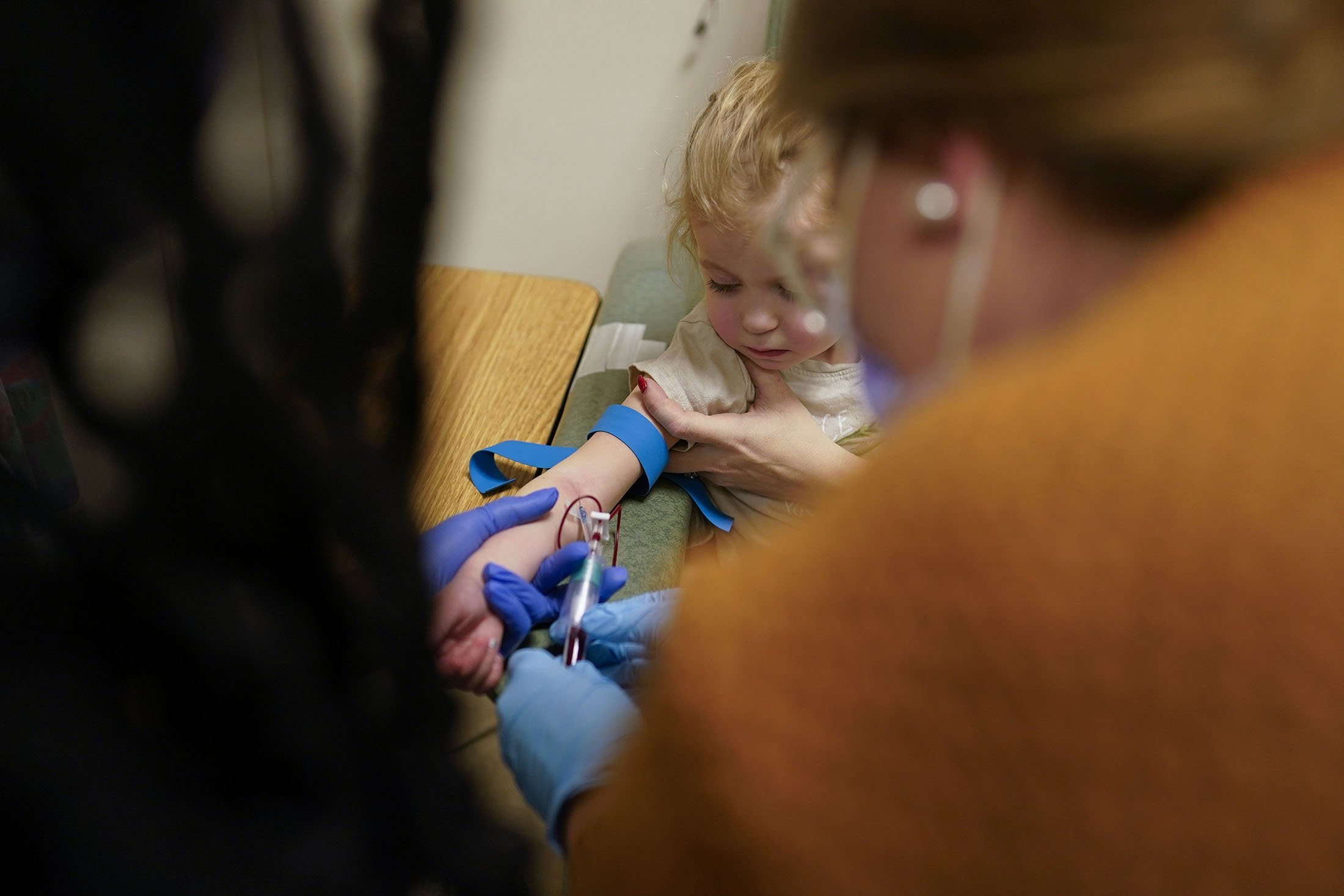 Alyssa Carpenter, 3, di lengannya sebagai perawat peneliti Michelle Harris (kiri), dan praktisi perawat praktik lanjutan Lauren Arrigoni (kanan), mengambil darah di Children's National Hospital di Washington, AS, 28 Februari 2022. (AP Photo)