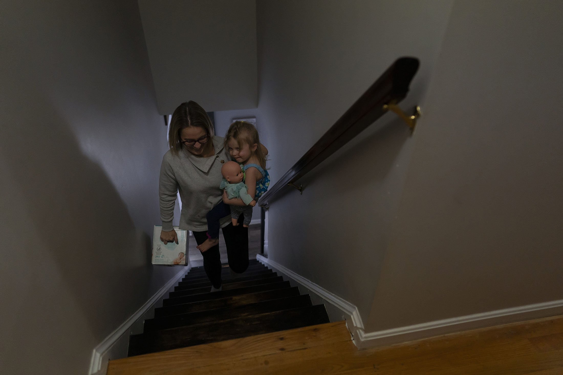 Tara Carpenter membawa putrinya, Alyssa Carpenter, 2, dan sekotak popok di lantai atas di rumah mereka di Haymarket, Virginia, AS, 28 Januari 2022. (AP Photo)