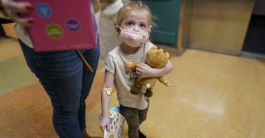 Alyssa Carpenter, 3, waits for the elevator with her mother, Tara Carpenter, with stickers and toys given to her during her followup visit to Children's National Hospital in Washington, U.S., Feb. 28, 2022. (AP Photo)