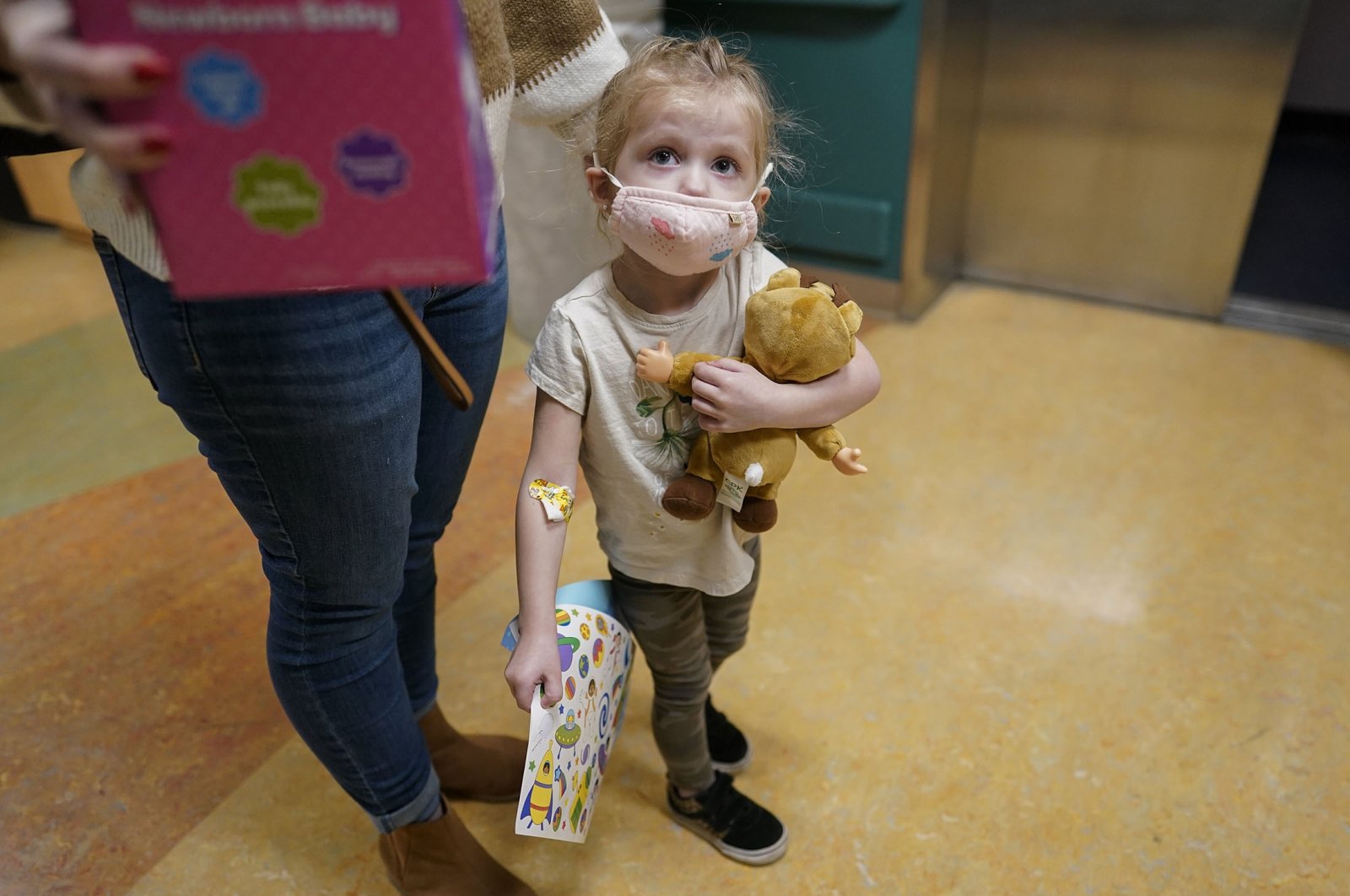 Alyssa Carpenter, 3, waits for the elevator with her mother, Tara Carpenter, with stickers and toys given to her during her followup visit to Children&#039;s National Hospital in Washington, U.S., Feb. 28, 2022. (AP Photo)