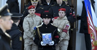 A serviceman carries the photo of Capt. Andrei Paliy, a deputy commander of Russia's Black Sea Fleet, during a farewell ceremony in Sevastopol, Crimea, March 23, 2022. (AP Photo)