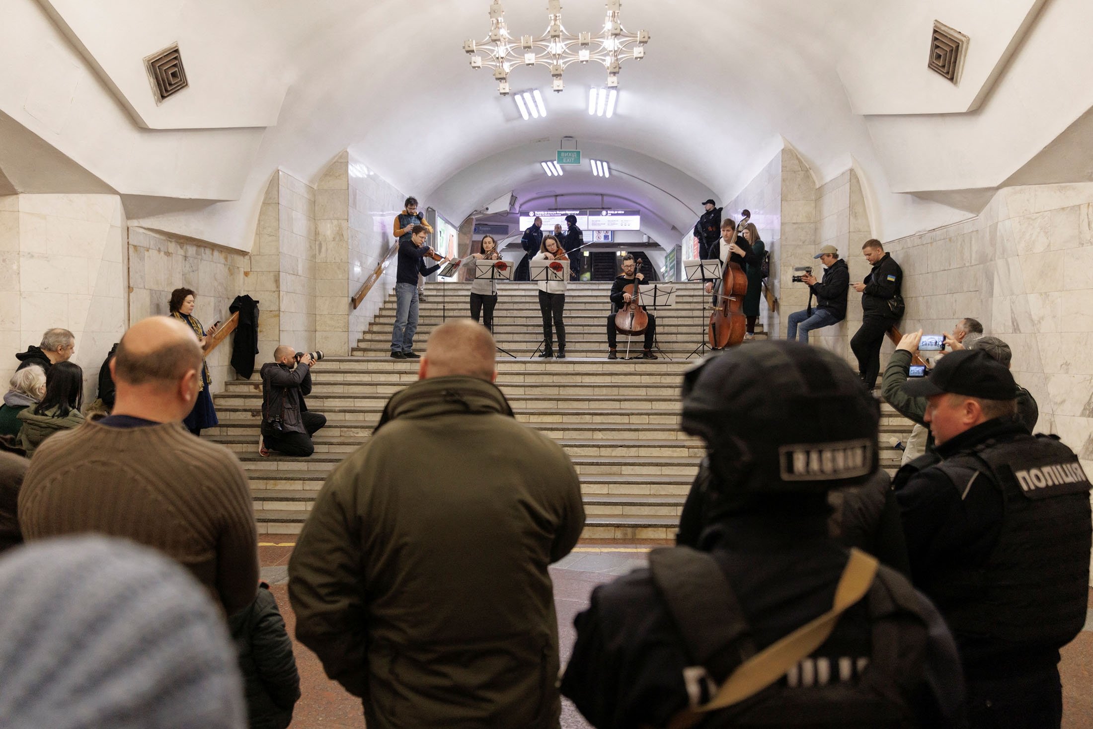 Orang-orang mendengarkan musik klasik yang dibawakan oleh musisi lokal di stasiun metro yang berfungsi sebagai tempat perlindungan bom saat serangan Rusia ke Ukraina berlanjut di Kharkiv, Ukraina, 26 Maret 2022. (Foto Reuters)