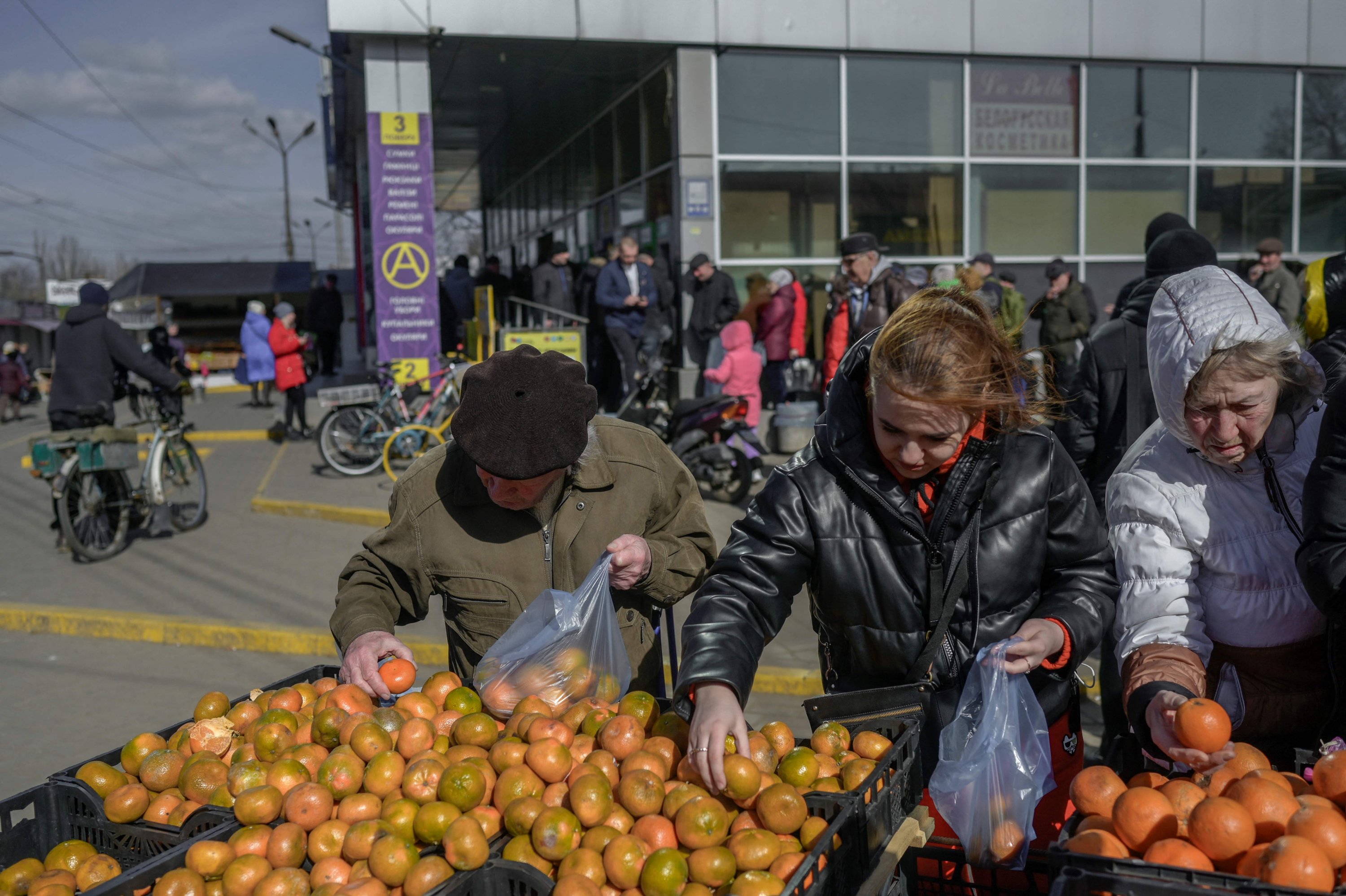 Orang-orang berbelanja buah di pusat kota Mykolaiv, kota utama di jalan menuju Odessa, pelabuhan terbesar Ukraina, 27 Maret 2022. (AFP Photo)