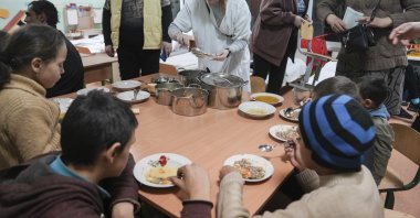 A kindergarten worker gives food to an internally displaced family from Mariupol in Zaporizhzhia, Ukraine, March 21, 2022. (AP Photo)