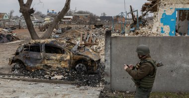 A Ukrainian service member walks past a burnt-out car, as Russia's attack on Ukraine continues, in the village of Krasylivka outside Kyiv, Ukraine, March 26, 2022. (Reuters Photo)