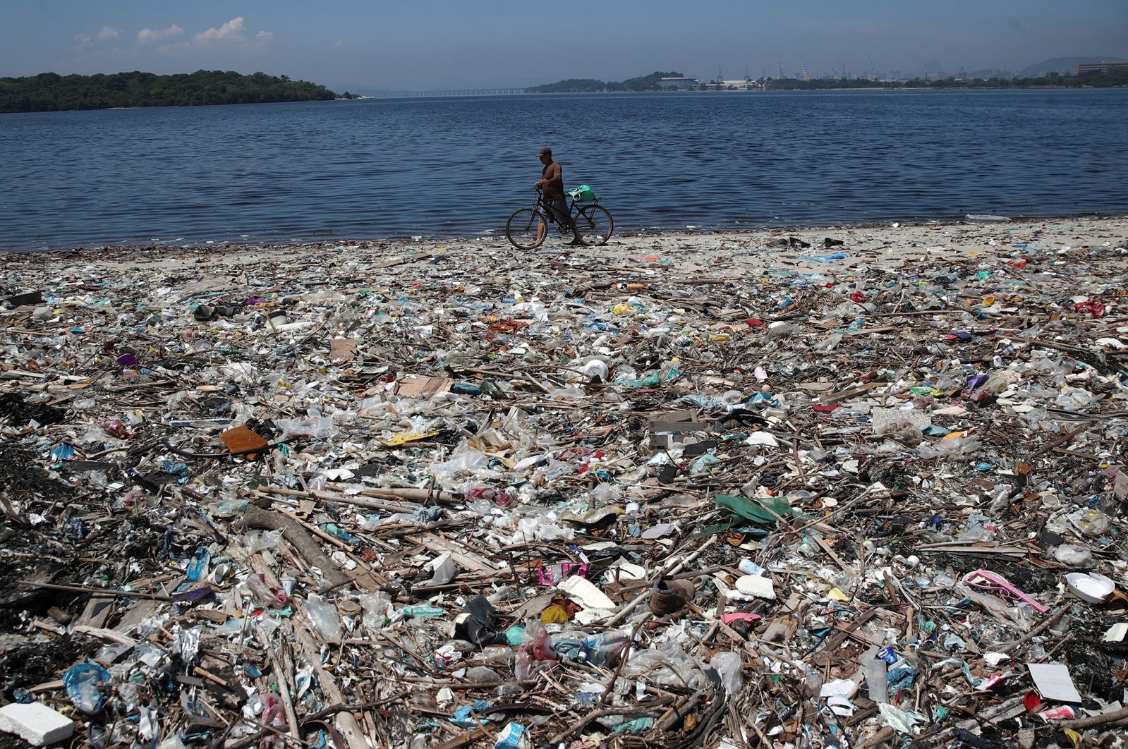 A man walks by garbage at a polluted beach on the banks of Guanabara Bay in Rio de Janeiro, Brazil, March 16, 2022. (Reuters Photo)