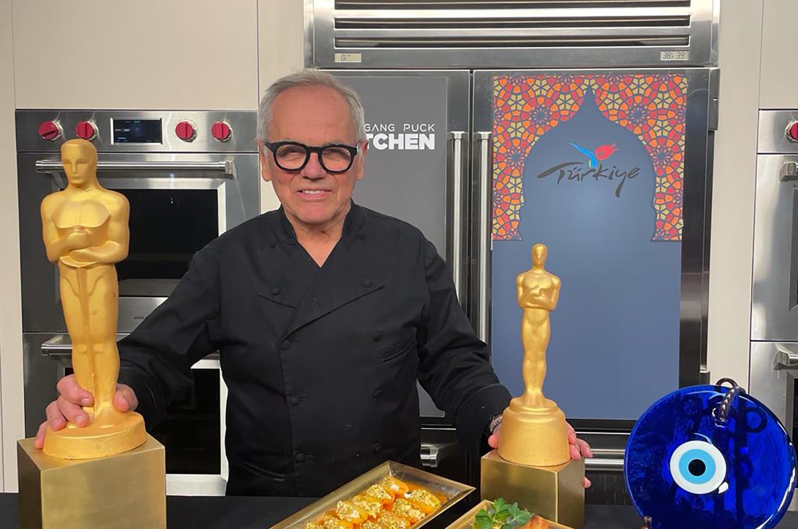 Chef Wolfgang Puck poses with Black Sea pide and Creamy Apricot Dessert prepared for the Academy Awards Governors Ball. (Photo courtesy of TGA)