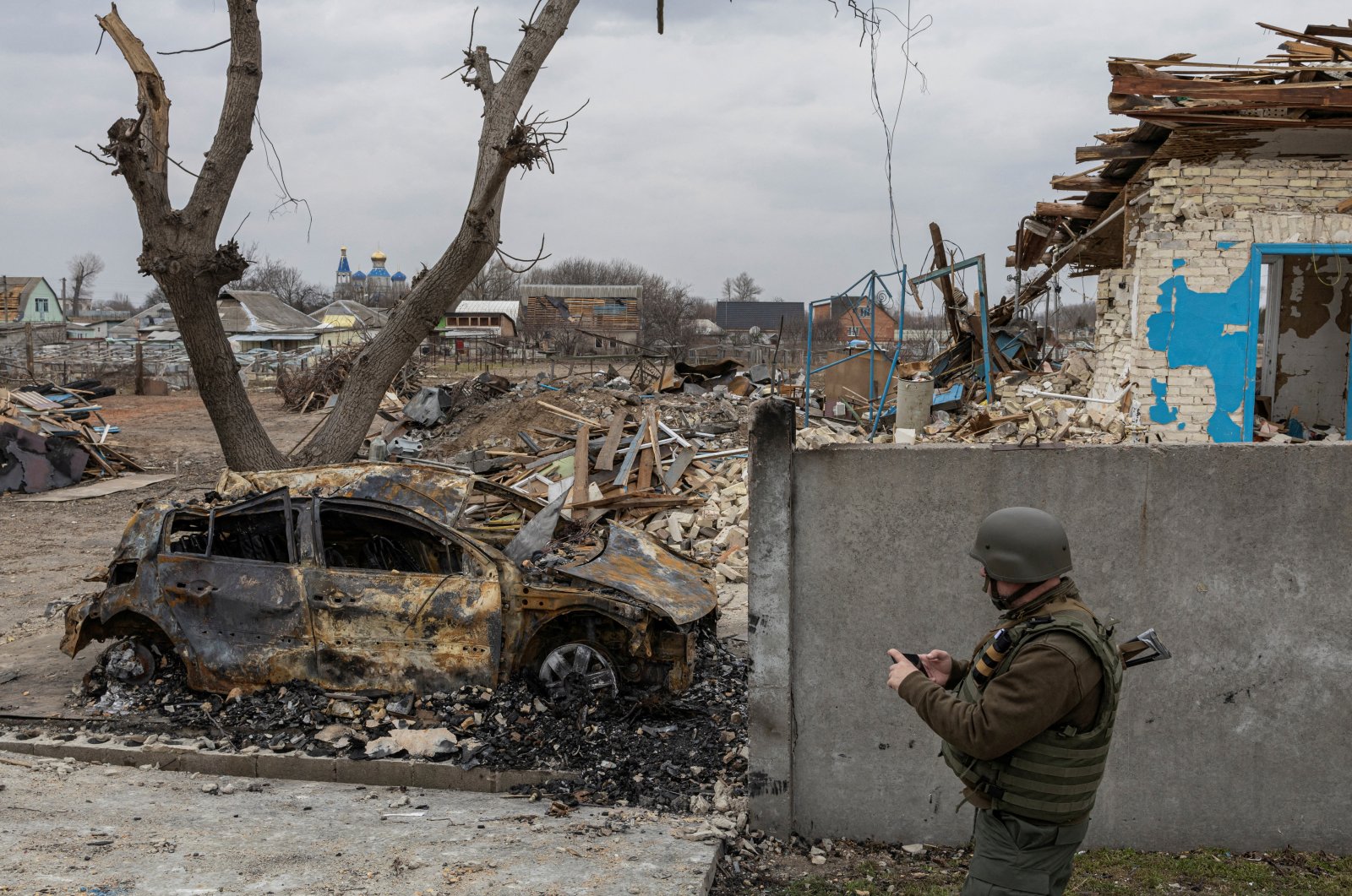 A Ukrainian service member walks past a burnt-out car, as Russia&#039;s attack on Ukraine continues, in the village of Krasylivka outside Kyiv, Ukraine, March 26, 2022. (Reuters Photo)