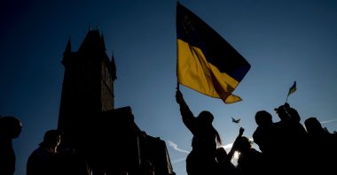 People display a Ukrainian flag as they watch the broadcast of the international charity concert "Save Ukraine – Stop War" streamed from Warsaw to the Old Town Square in Prague, Czech Republic, March 27, 2022. (AFP Photo)