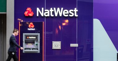 Motion blurred man walks past a Natwest Bank cash machine, Manchester, U.K., July 6, 2019. (Shutterstock Photo)