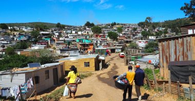 South Africans walk down a street amid informal settlements, near Cape Town, South Africa. (ShutterStock Photo)