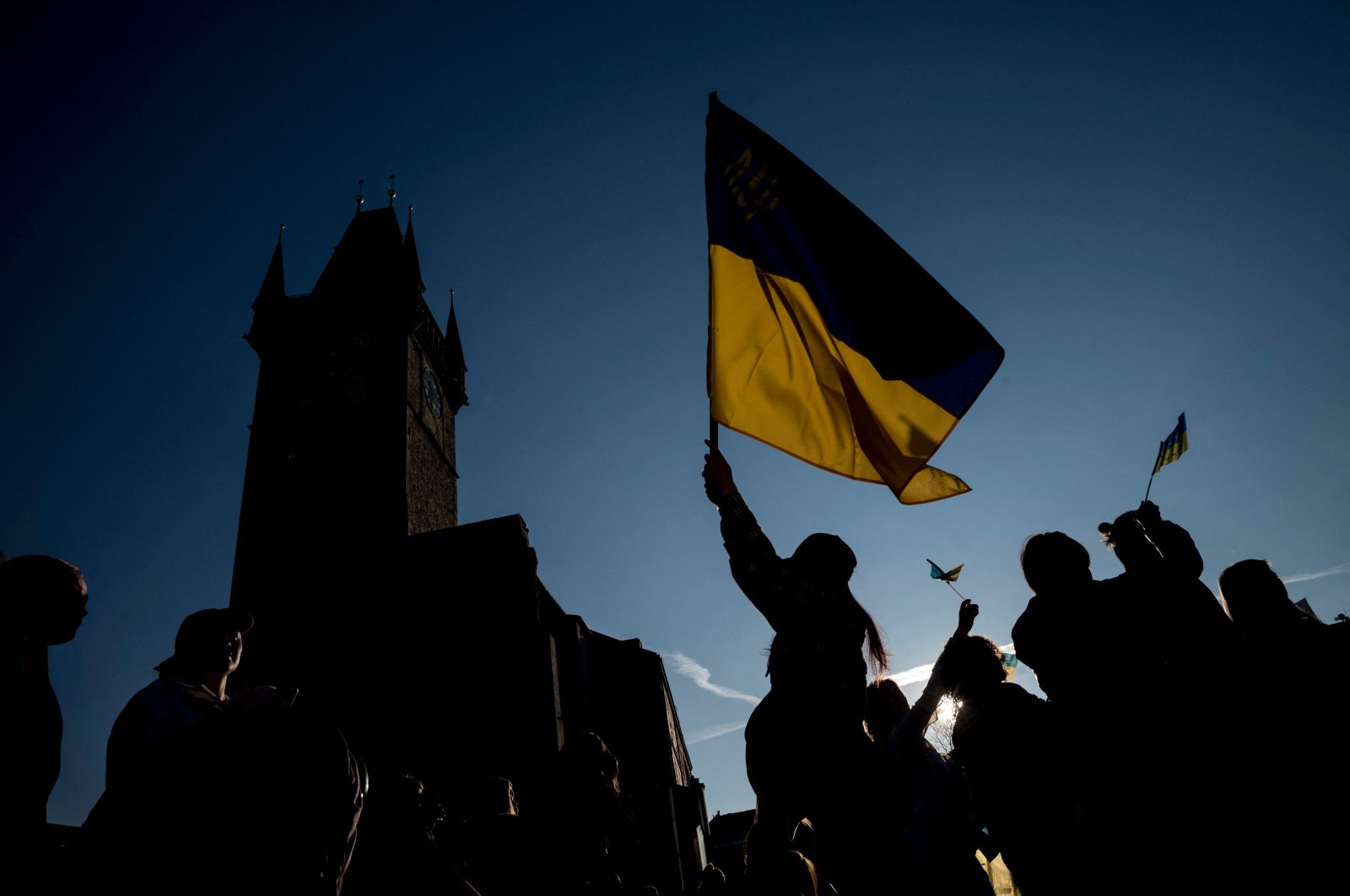 People display a Ukrainian flag as they watch the broadcast of the international charity concert "Save Ukraine – Stop War" streamed from Warsaw to the Old Town Square in Prague, Czech Republic, March 27, 2022. (AFP Photo)