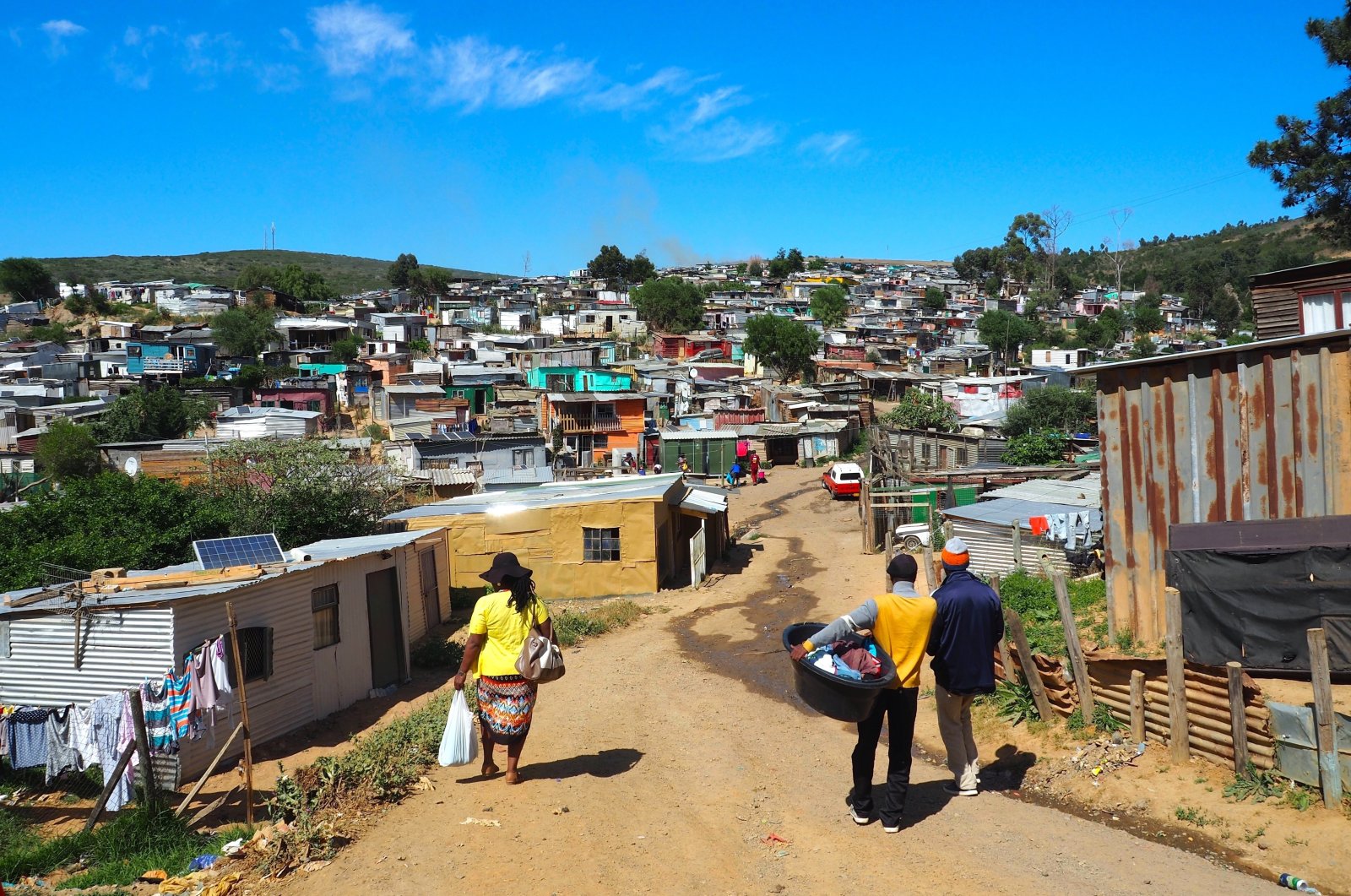 South Africans walk down a street amid informal settlements, near Cape Town, South Africa. (ShutterStock Photo)
